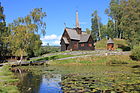 Stavkirken fra Garmo i Gudbrandsdalen ligger vakkert til ved en av de mange dammer og tjern som preger området.