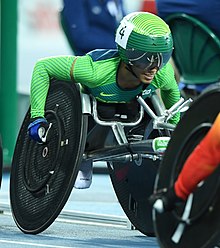 Women in green clothes with green helmet in a silver and black wheelchair.