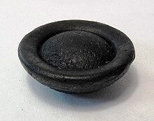 Aerodynamically shaped australite; the button shape is caused by ablation of molten glass in the atmosphere during reentry. Australite back obl.jpg