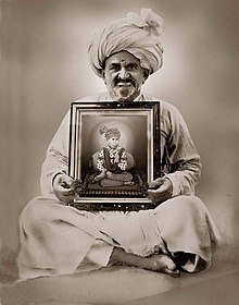 A digitally enhanced b/w picture of Abjibapashri. A man smiling in white coloured traditional Gujarati cloths and turban