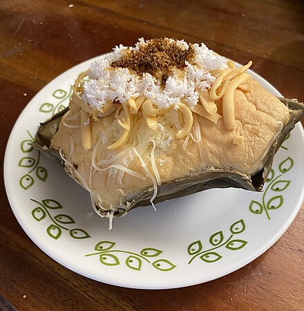 A large bibingka topped with grated coconut, cheese and muscovado sugar