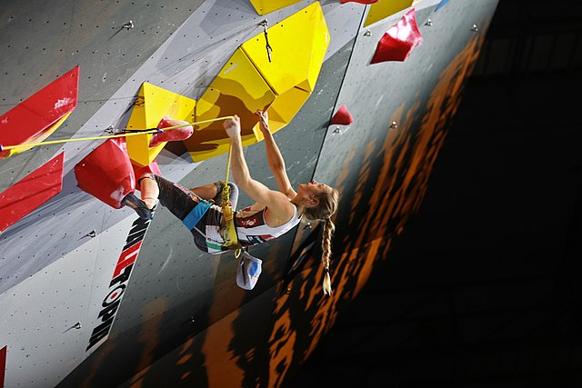 Jessica Pilz clipping her rope into a pre-bolted quickdraw in the final of the women's lead climbing event at the 2018 World Championships