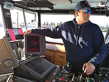 Guy Mitchell, a captain aboard the Guemes Island ferry, checks vessel traffic during a crossing April 11, 2020. Mitchell is one of seven crew members, including the ferry manager, to possess a 100-ton master's license. Guy Mitchell, a captain aboard the Guemes Island ferry.jpg