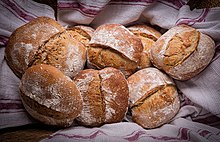 Belles boules de pain portant des restes de farine et une ligne tracée au milieu.