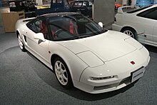 Photographie d'une voiture de sport blanche vue de trois-quarts, de haut, en exposition.