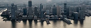 Wall Street West as seen from One World Trade Center in 2023 Jersey City skyline, Exchange Place waterfront at sunset (cropped).jpg