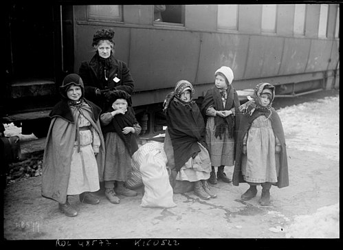 5 niños y una dama en el andén de una estación.