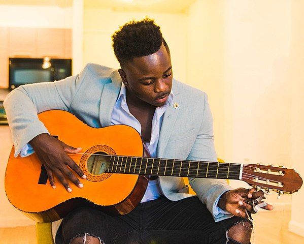 Man turning tuning pegs to tune guitar