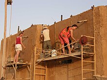 Applying mud plaster to an outside wall Mud plaster over straw bales wall.jpg
