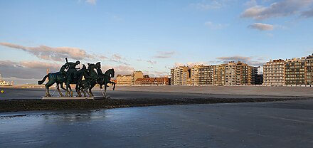 The beachfront of Nieuwpoort-Bad; in the foreground is Men, a statue of several men on horseback riding out of the sea towards town.