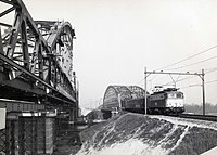 Locomotief uit 1100 over de oude spoorbrug. Links de nieuwe brug in aanbouw.