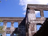 Ruinierte Steinmauer, die blauen Himmel durch Fensterlöcher zeigt.