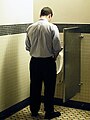 Hombre orinando en un urinario de pared.