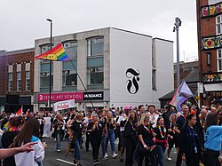 Humberside Fire and Rescue personnel and a tall Pride flag defaced with a smiley face flying at the Pride in Hull parade.