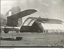 View past the tail of a Beaufighter of a hangar under construction 1943 Vivigani Airfield Beaufighter and Hangar 1943.jpg