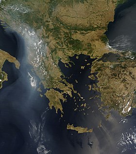 A satellite view of the Balkans and Greece. Clouds and smoke trails are seen above the Balkans and trailing south into the Ionian Sea.