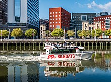 Barco turístico Bilboats en la ría a su paso por el paseo de Uribitarte