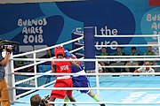 Deutsch: Boxen bei den Olympischen Jugendspielen 2018 Tag 12, 18. Oktober 2018 - Finale Fliegengewicht Mädchen – Martina La Piana (Italien, blau) schlägt Adijat Gbadamosi (Nigeria, rot) 5-0; Ringrichter ist James Beckles (Trinidad und Tobago). English: Boxing at the 2018 Summer Youth Olympics on 18 October 2018 – Girl's flyweight Gold Medal Bout - Martina La Piana (Italy, blue) beats Adijat Gbadamosi (Nigeria, red) 5-0; Referee is James Beckles (Trinidad and Tobago). Español: Boxeo en los Juegos Olímpicos Juveniles de Verano de 2018 en 18 de octubre de 2018 - Combate a medalla de oro de peso mosca para mujeres: Martina La Piana (Italia, azul) le gana a Adijat Gbadamosi (Nigeria, roja) 5-0; El árbitro es James Beckles (Trinidad y Tobago).