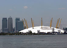 El Millennium Dome, con el complejo Canary Wharf al fondo, visto desde el Támesis. El logotipo de Londres 2012, actualmente retirado del Dome, puede verse promocionándolo como sede olímpica.