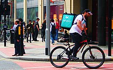 A Deliveroo cycle delivery worker in Manchester, England Deliveroo Cyclist on a Bike in Manchester.jpg