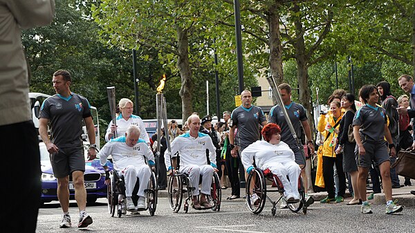 A group of torchbearers in wheelchairs bringing the Paralympic flame through Canary Wharf