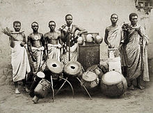 Photo de six personnes noires derrière leurs différents tambours et en tenue traditionnelle.