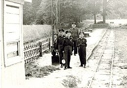 Pioniereisenbahner am Bahnsteig. Die beiden Bäume im Hintergrund stehen heute noch. Sie stehen auf dem eingezäunten Gelände des Spreeauenparks.