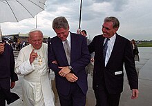 Ambassador-designate Flynn (right) accompanies Pope John Paul II (left) and President Clinton (center) during the pope's arrival at Stapleton International Airport for the 1993 World Youth Day celebration in Denver, Colorado Photograph of President William J. Clinton Talking with Pope John Paul II on the Tarmac at Stapleton International Airport in Denver, Colorado - NARA - 3164807 (4).jpg