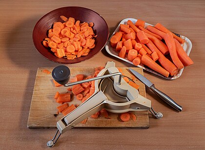 Preparação e corte de cenouras com um cortador de legumes Moulinex. A cenoura (Daucus carota) é um vegetal de raiz, tipicamente de cor laranja, nativa da Europa e Sudoeste Asiático. A parte mais comumente consumida da planta é a raiz principal. As raízes contêm grandes quantidades de alfa e betacaroteno e são uma boa fonte de vitamina A, vitamina K e vitamina B6. As cenouras são comumente consumidas cruas ou cozidas em várias cozinhas. (definição 4 748 × 3 473)