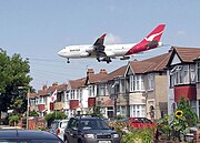 هبوط طائرة Qantas 747-400 تعبرُ قريبة من البيوتِ على مدرج مطار هيثرو لندن، إنجلترا