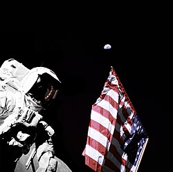 NASA Apollo 17 astronaut Harrison Schmitt deploying an American flag on the Moon during a gibbous phase of the Earth (photo by Eugene Cernan)