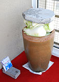 Suan cai preparation – a heavy stone is placed atop Chinese cabbages in a large pot. The cabbage will sink naturally in a few weeks as the fermentation begins. Salt, seen in the plastic bag in the lower left corner, is usually the only additive used.