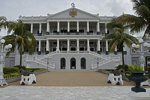 A balck and white building with garden in front.