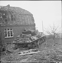 An Achilles 17-pdr tank destroyer uses a building as cover in Hassum, near Goch in Germany, 20 February 1945