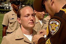 A PGSO corporal in service dress "A" uniform pins a collar device onto a U.S. Navy chief petty officer's uniform in September 2008. US Navy 080916-N-0967W-001 Chief Yeoman Melissa Salley stands at attention as her husband, Prince George's County Deputy Sheriff Corporal James Salley pins anchors on her collar.jpg