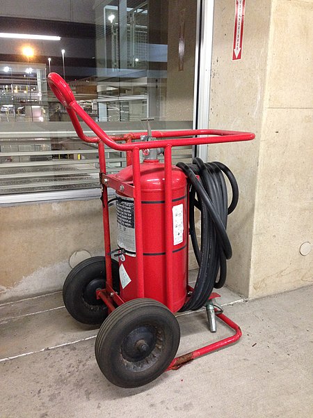 Wheeled fire extinguisher and a sign inside a parking lot