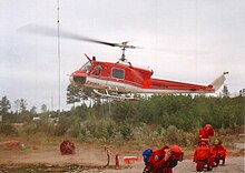 A Bell 204B (upgraded to a "C" model) arrives to pick up its Ontario Ministry of Natural Resources firefighting crew on Fire 141, 1995 Bell204CandFireFighters04.JPG