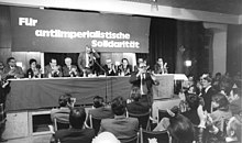 Parteitag 1976 mit SED-Gästen, darunter Paul Verner (4.v.r.), Günter Mittag (4.v.l.), Joachim Herrmann (3.v.l.), Herbert Häber (3.v.r.) und Michael Kohl (vor dem Präsidium stehend) (Quelle: Wikimedia)