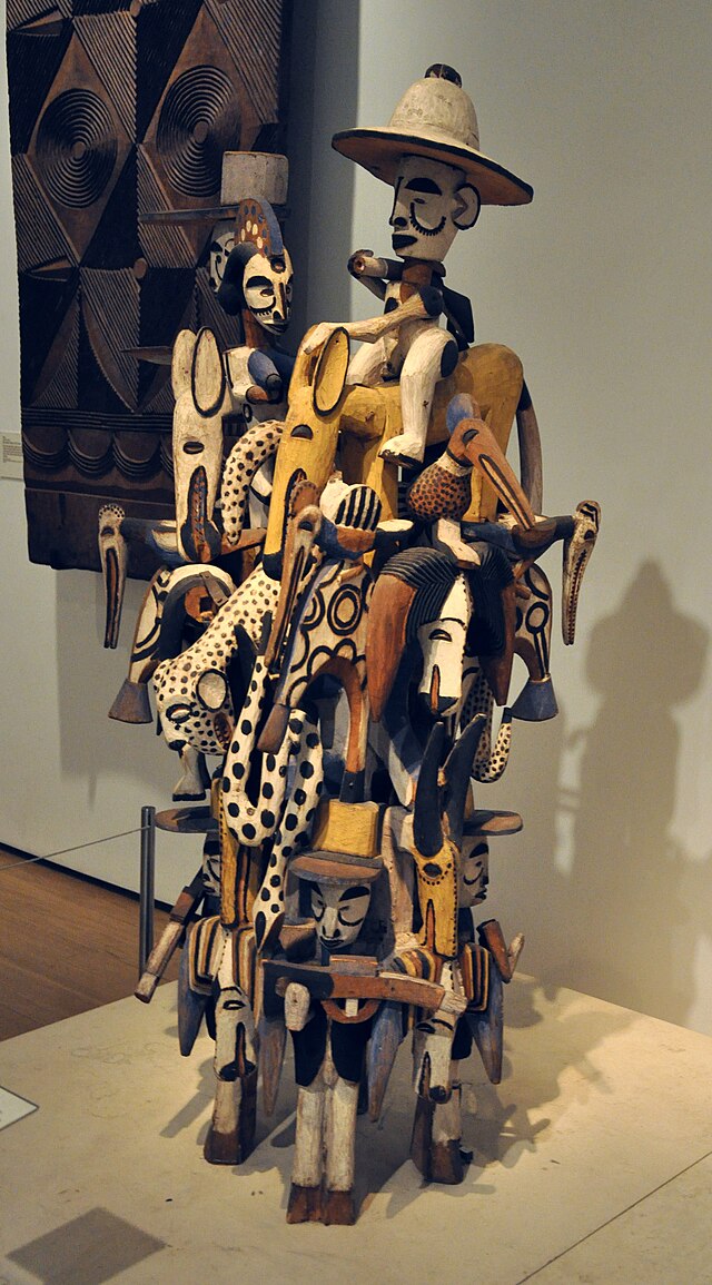 A photo of a complex wooden carving of animals, people and spirits laid on each other to about 2 meters in height