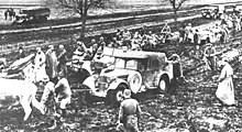 una fotografia in bianco e nero di truppe e animali che tirano fuori i veicoli dal fango