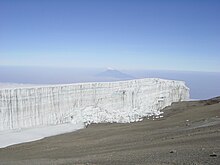 Vertical margin wall of the Rebmann Glacier in 2005 with Mount Meru, which is 70 kilometres (43 mi) away, in the background.