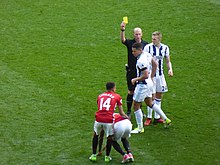 Dean brandishing a yellow card in a match between Manchester United and West Bromwich Albion in April 2017. Manchester United v West Bromwich Albion, April 2017 (24).JPG
