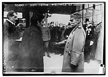 černobílá fotografie, dva muži v popředí, vzadu asi vojáci