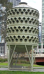 Large pigeon trap/coop/loft at Batman Park, Melbourne. Designed specifically to encourage nesting and allow removal of fertilised eggs to prevent population growth, it was a landmark in its own right before its removal, for lack of success, around 2015. Pigeon trap melbourne.jpg