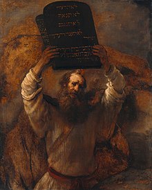 Esta es una imagen de un óleo sobre lienzo de Rembrandt (1659) de un hombre barbudo que representa a Moisés con dos tablas de piedra de los diez mandamientos en alto con ambas manos.