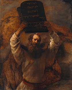 This is an image of an oil on canvas picture by Rembrandt (1659) of a bearded man representing Moses with two tablets of stone of the ten commandments held high in both hands.