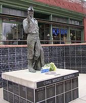 The Coal Miners' Memorial in Roslyn. Note the radio station film set from the Northern Exposure television series in the background. Roslyn-miner-memorial-and-KBHR.JPG