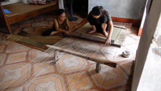 Traditional lying down-style sedge mat weaving in Vietnam, two people weaving phase, unknown location.png