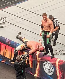 Will Ospreay stands over a bloodied Kenny Omega during their match. Will Ospreay v Kenny Omega, AEW Forbidden Door 2023, 2023-06-25 07.jpg