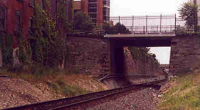 The north entrance to the 7th Street cut, with Walnut Street passing overhead as the stone walls begin on either side